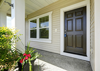 Open porch with concrete floor, column and entrance brown door